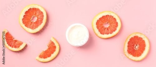 Fotografia, Obraz Vitamin c body moisturizer cream jar with sliced grapefruit on pink background