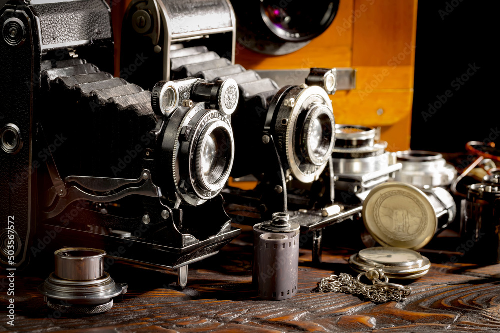 Naklejka premium An old camera in a composition on an old background, on a table