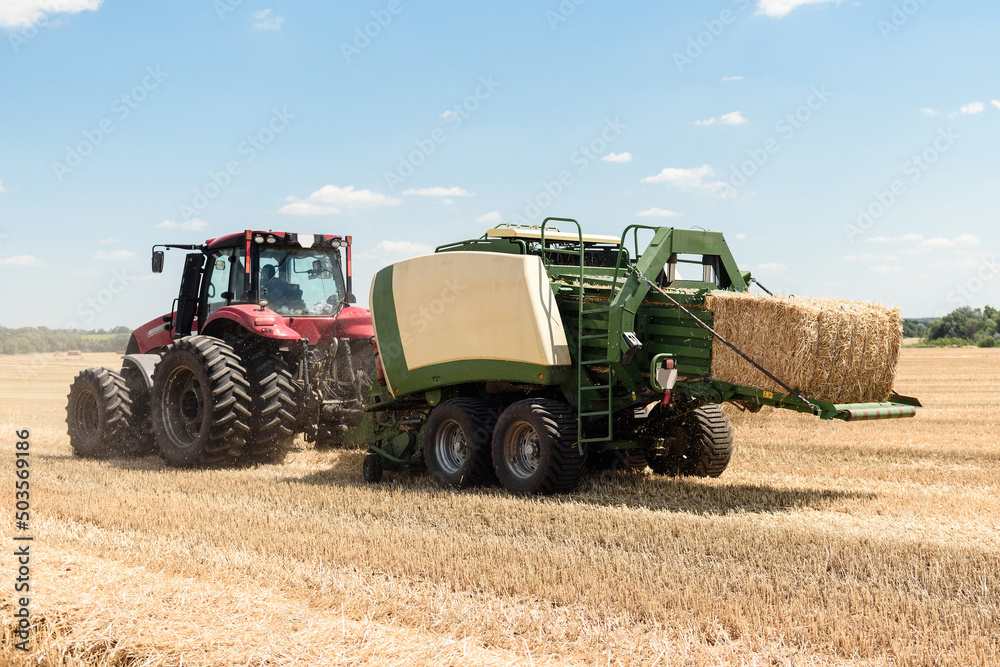 Tractor collects straw in bales on the field. special agricultural machinery. Harvesting hay, straw. Field with bales Tractor collects straw in bales on the field. special agricultural machinery. Harvesting hay, straw. Field with bales