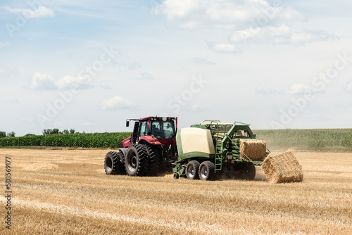 Tractor collects straw in bales on the field. special agricultural machinery. Harvesting hay  straw. Field with bales