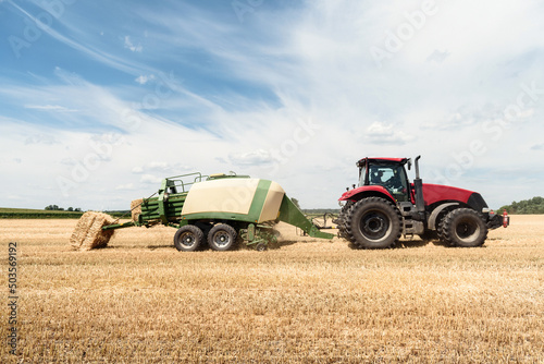 Tractor collects straw in bales on the field. special agricultural machinery. Harvesting hay  straw. Field with bales