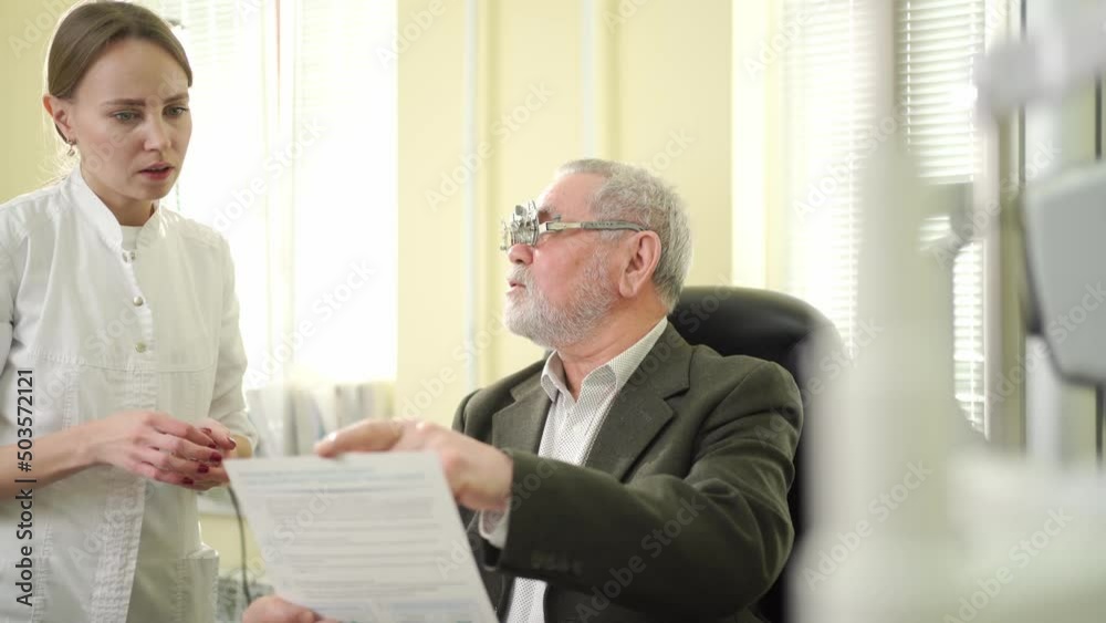 ophthalmologist makes selection of lenses, diagnoses a elderly man's vision. ophthalmologist makes selection of lenses, diagnoses a elderly man's vision.