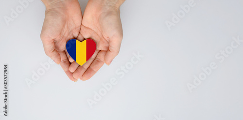The national flag of Romania of arms in female hands. Flat lay, copy space.
