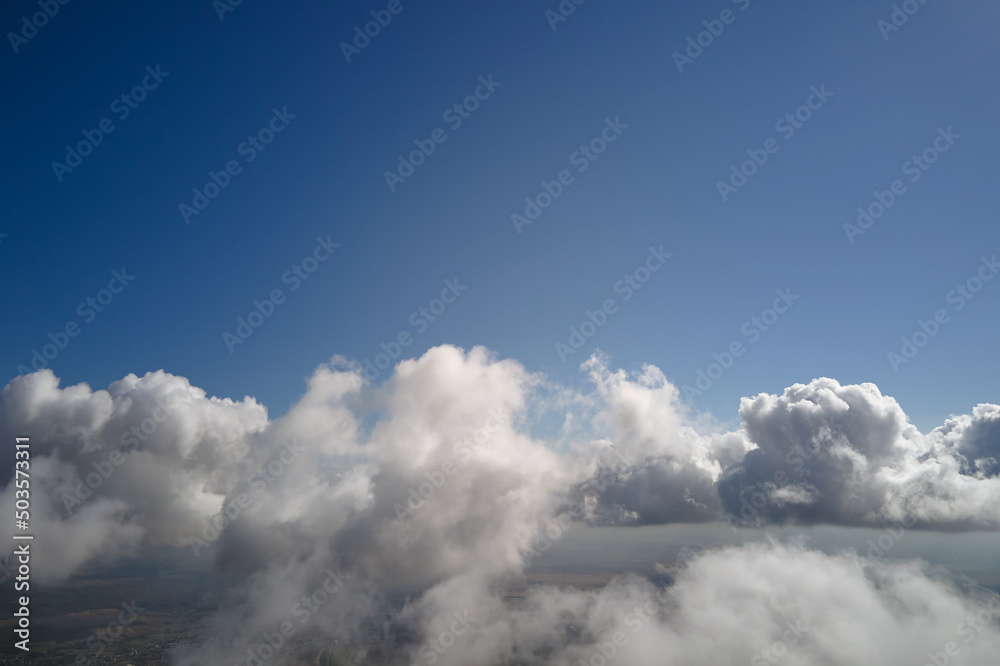 Aerial view from airplane window at high altitude of earth covered with white puffy cumulus clouds Aerial view from airplane window at high altitude of earth covered with white puffy cumulus clouds