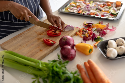 Midsection of african american mid adult woman cutting red bell pepper while preparing food at home photo