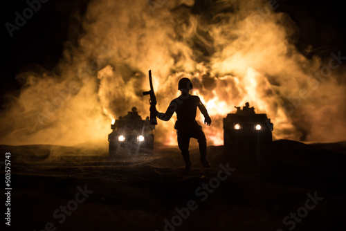 War Concept. Battle scene on war fog sky background, Fighting silhouettes Below Cloudy Skyline at night. Army vehicle with soldiers artwork decoration. Selective focus