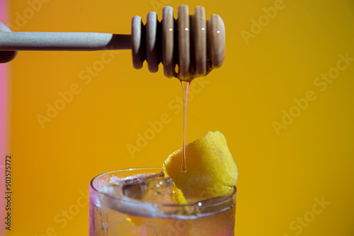 Honey dripping over lemon garnish on cocktail glass