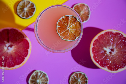 Grapefruit craft cocktail with slices surrounding coupe glass from overhead shot