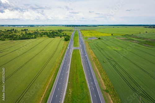 Asphalt highway through green summer field. Aerial view