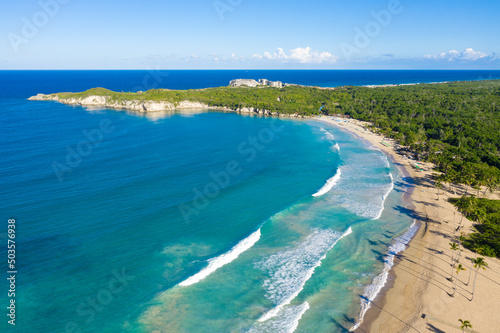 Macao beach with sandy coastline, turquoise water and stone cliff. Famous shore for surfing in Dominican Republic. Aerial view