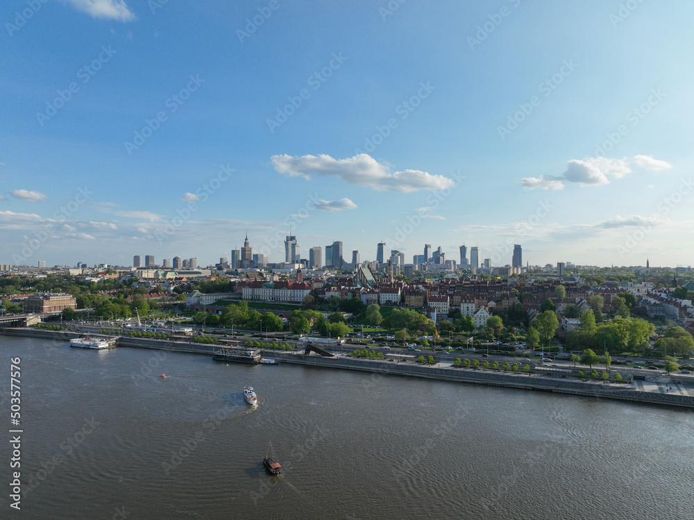 Fototapeta premium widok z lotu ptaka na centrum Warszawy, panorama miasta, wieżowce i rzekę Wisła, wiosna, zielone drzewa i niebieskie niebo
