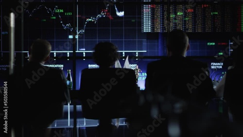 A group of analysts is watching the graphs and scales on the screens. A team of specialists is monitoring the changes. Numbers and indicators on a digital scoreboard. Currency. Cryptocurrency. Banking photo