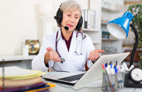 Female doctor in headphones with microphone consults patient on the Internet