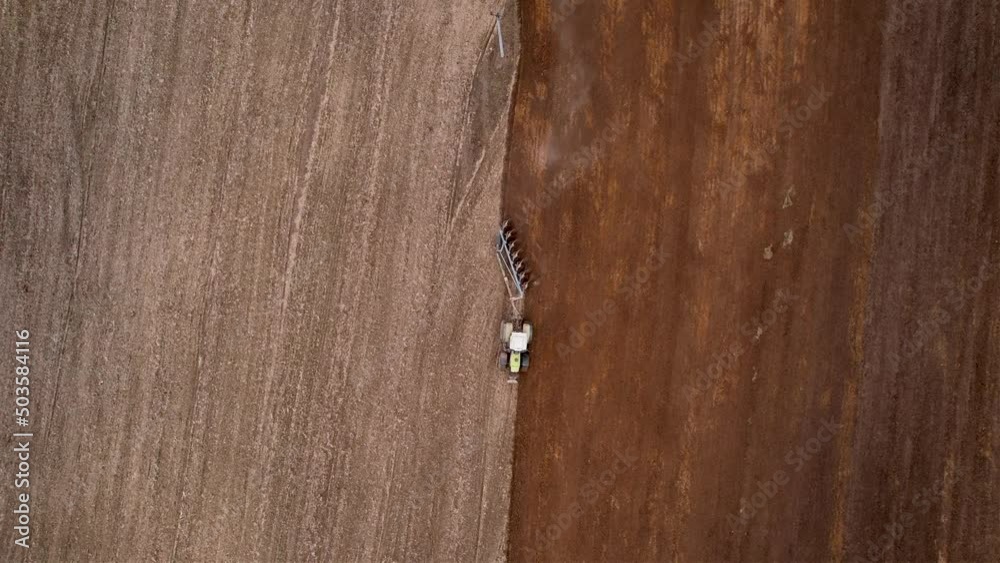 Tractor plowing field, drone view. Cultivated land and soil tillage. Tractor with disc cultivator on cultivating. Agricultural tractor on field cultivation. Tractor disk harrow on plowing field. 