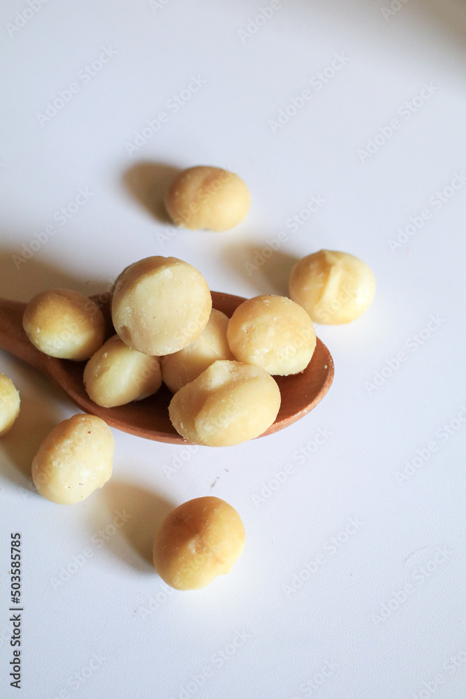 Macadamia nuts in wooden spoon on white background. Healthy product. Macadamia nuts are a source of protein packed with healthy vitamins. Macadamia nuts in wooden spoon on white background. Healthy product. Macadamia nuts are a source of protein packed with healthy vitamins.