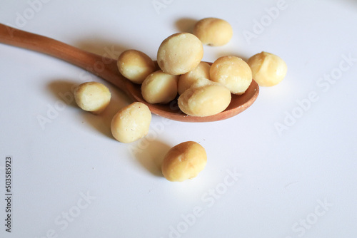 Macadamia nuts in wooden spoon on white background. Healthy product. Macadamia nuts are a source of protein packed with healthy vitamins.