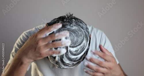 man cleaning his hair with a anti dandruff shampoo foam, using hair care product photo