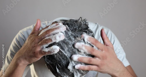 man hand cleaning his hair with a anti dandruff shampoo at home photo