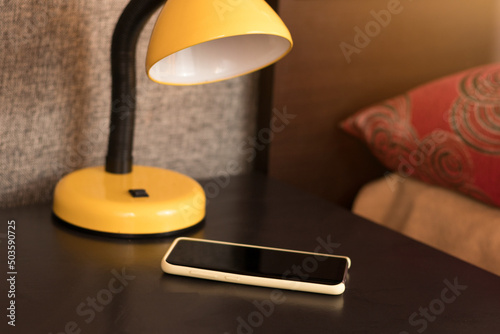 Behang bedroom in summer with smartphone and lamp on the nightstand next to the bed
