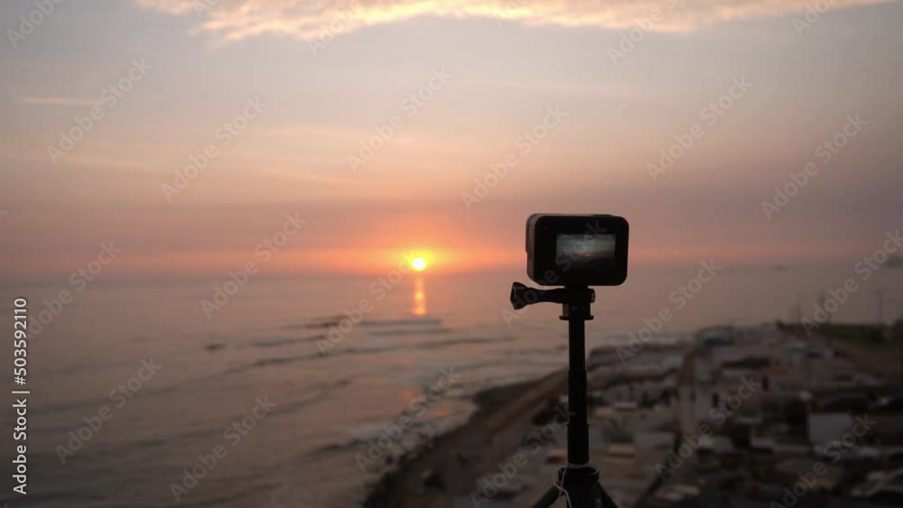 closeup of a small action camera recording a sunset on the beach and the waves of the sea in 4k closeup of a small action camera recording a sunset on the beach and the waves of the sea in 4k