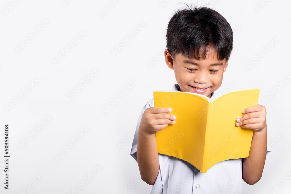 Asian toddler smile happy wearing student thai uniform red pants standing holding and reading a book in studio shot isolated on white background, Portrait little children boy preschool, Back to school Asian toddler smile happy wearing student thai uniform red pants standing holding and reading a book in studio shot isolated on white background, Portrait little children boy preschool, Back to school