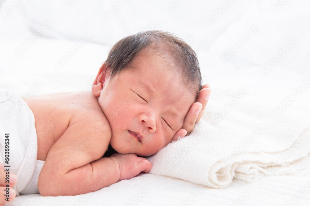Close up of newborn baby deeply sleeping and mom supports the baby's head tenderly on the white bed. Portrait of cute infant child and parent love. Comfort and safety sleep on bed. Close up of newborn baby deeply sleeping and mom supports the baby's head tenderly on the white bed. Portrait of cute infant child and parent love. Comfort and safety sleep on bed.