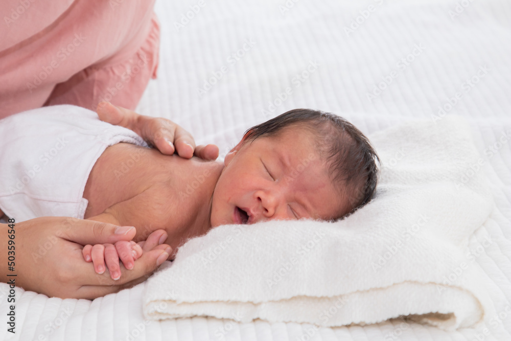 Selective focus of baby massage therapy for baby happy and reduce baby crying with sleep more peacefully, Newborn baby sleeping on bed and mother touch baby with love. Selective focus of baby massage therapy for baby happy and reduce baby crying with sleep more peacefully, Newborn baby sleeping on bed and mother touch baby with love.