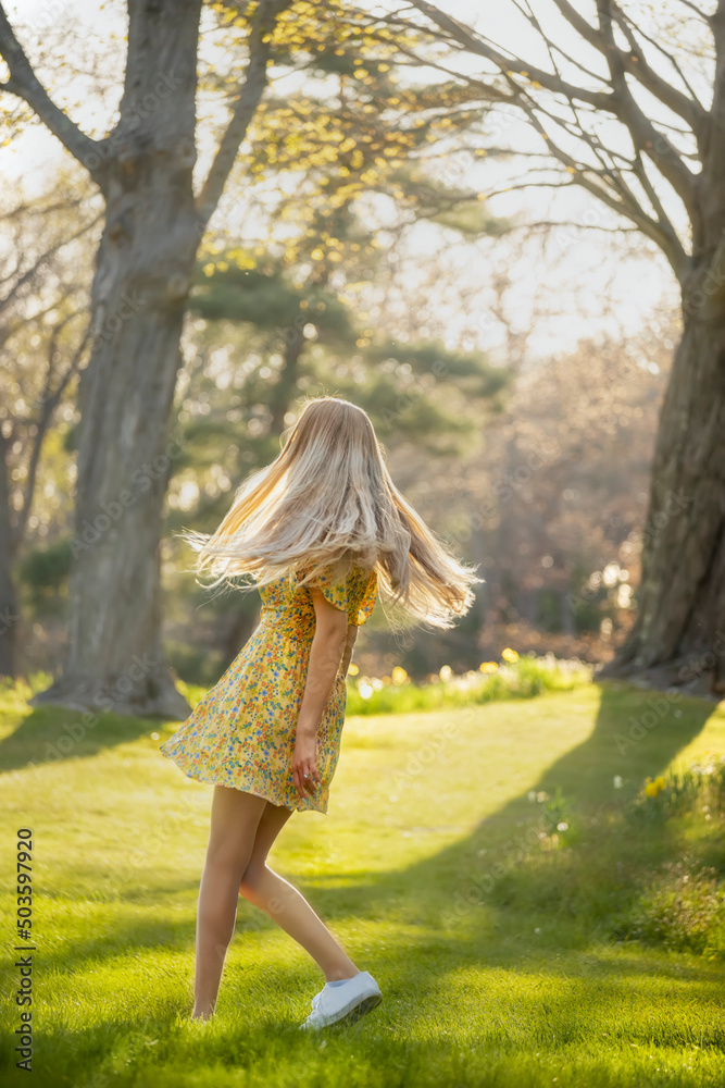 A girl in a spring dress is spinning in a spring park. A girl in a spring dress is spinning in a spring park.