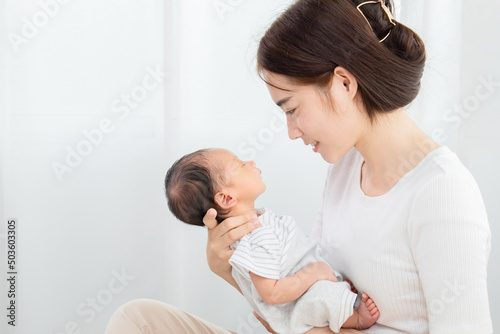 Asian mother holding her baby in her arm and put her nose on baby's nose. Touching of love between mother and child concept, mother lifting and looking he while the son is sleeping. Love concept.
