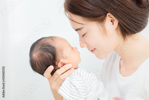 Asian mother holding her baby in her arm and put her nose on baby's nose. Touching of love between mother and child concept, mother lifting and looking he while the son is sleeping. Love concept. © Rakchanok