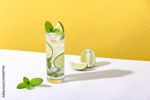 Ice and mojito in a glass lie on the table with a strong shadow photo
