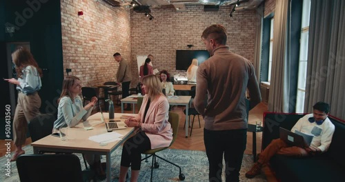 Happy young company boss businessman, corporate team leader enters office, meets colleagues and joins teamwork process.