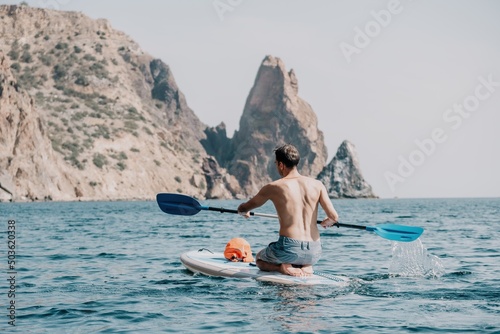 Side view foto of a man swiming and relaxing on the sup board. Sportive man in the sea on the Stand Up Paddle Board SUP. The concept of an active and healthy life in harmony with nature.