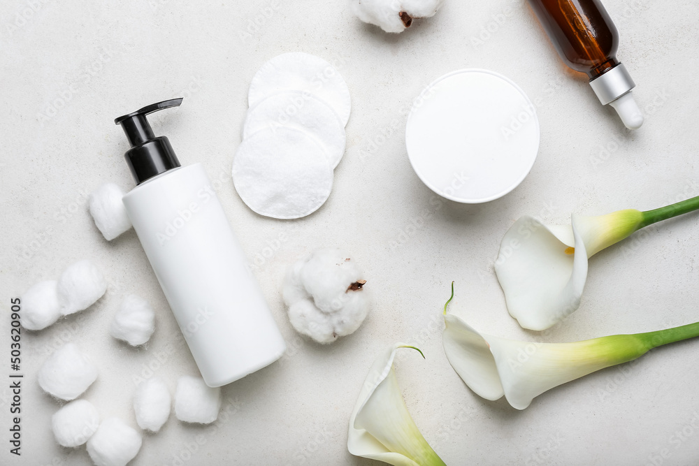 Composition with cosmetic products, cotton pads, balls and flowers on light background Composition with cosmetic products, cotton pads, balls and flowers on light background