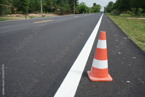 Red rubber cones are placed in the paved road. © suwichan