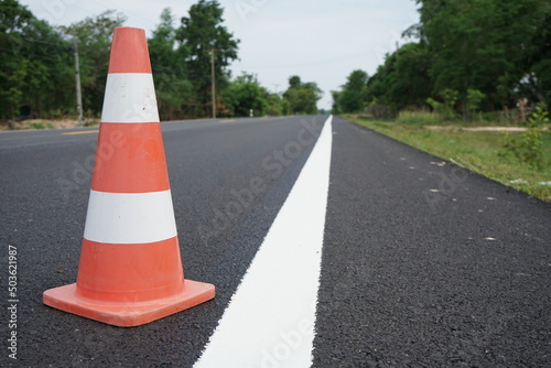 Red rubber cones are placed in the paved road. © suwichan