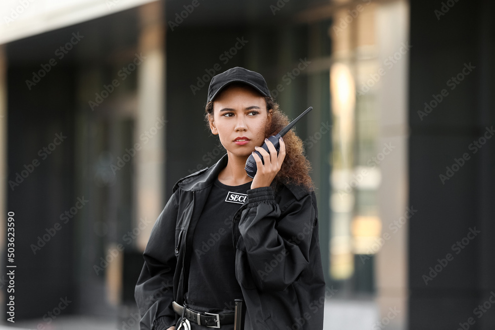 © Pixel-Shot - African-American female security guard with radio transmitter near building outdoors © Pixel-Shot - African-American female security guard with radio transmitter near building outdoors