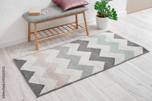 Fotografie Soft carpet and comfortable bench on light wooden floor in room interior