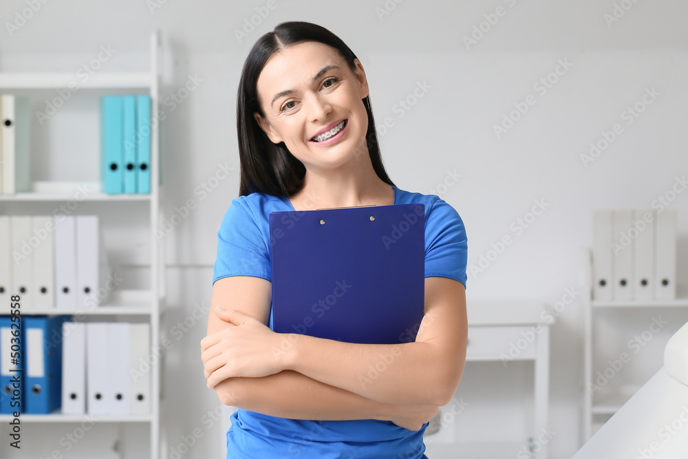 Beautiful woman with dental braces and clipboard in clinic Beautiful woman with dental braces and clipboard in clinic