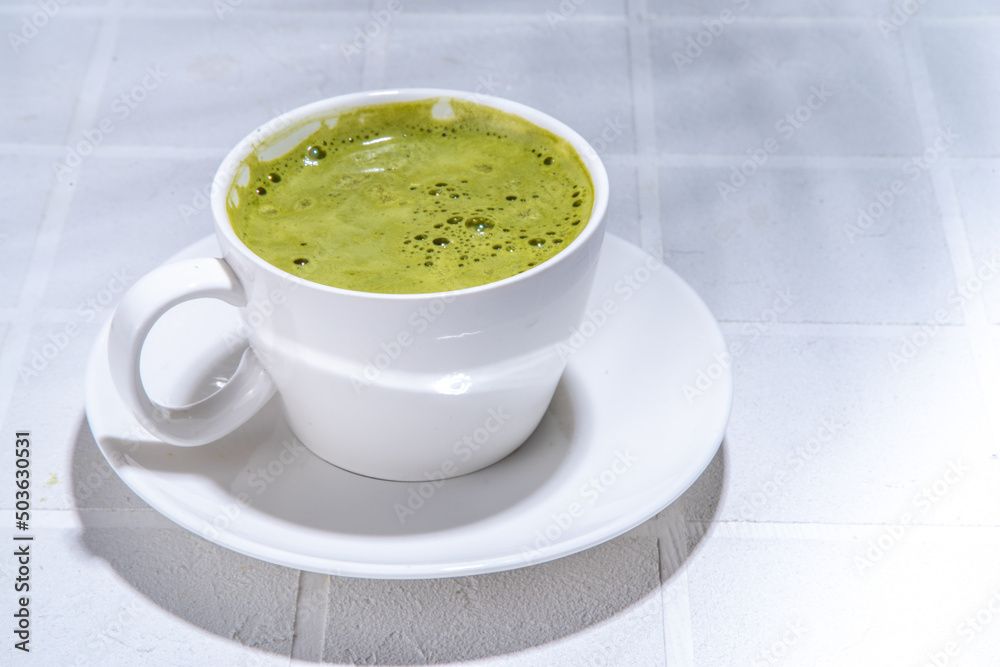 Matcha green tea latte on white concrete background with hard light, one cup of matcha drink in woman hands, top view copy space Matcha green tea latte on white concrete background with hard light, one cup of matcha drink in woman hands, top view copy space