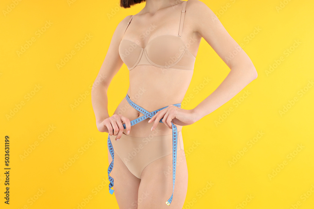Concept of weight loss, young woman on yellow background