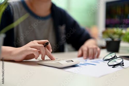 Female college student using calculator, doing her financial homework
