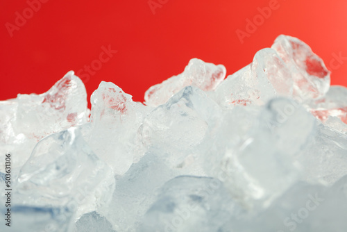Ice for drinks on red background, close up