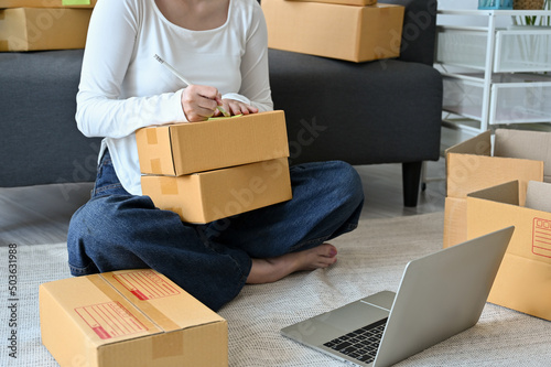 Female organising her product orders packaging, writing customer address