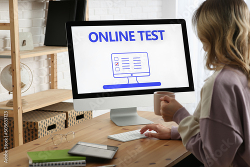 Woman taking online test on computer at desk indoors