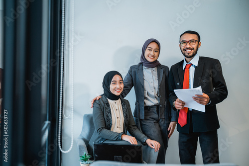 portrait of businessman at meeting with his two female muslim employee