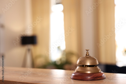 Hotel service bell on wooden reception desk. Space for text