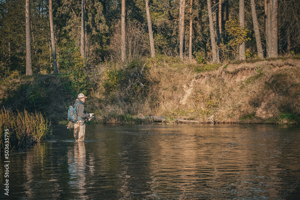 Fisherman in Waders on the forest river.