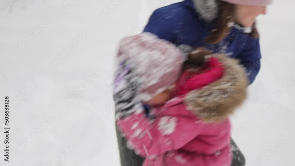 Dynamic video of happy mother and daughter are having fun while playing with snow together. Child girl is throwing snowball in her mother, and mom takes revenge on daughter, 4k