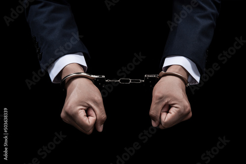 Handcuffed hands of a prisoner on black background. Fototapet